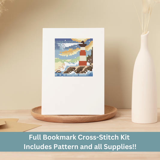 Handmade lighthouse cross-stitch greeting card displayed on a wooden tray with a neutral background.