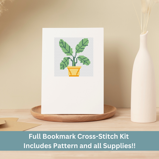 Cross-stitch greeting card featuring a green leafy houseplant in a yellow pot, stitched on Aida cloth.