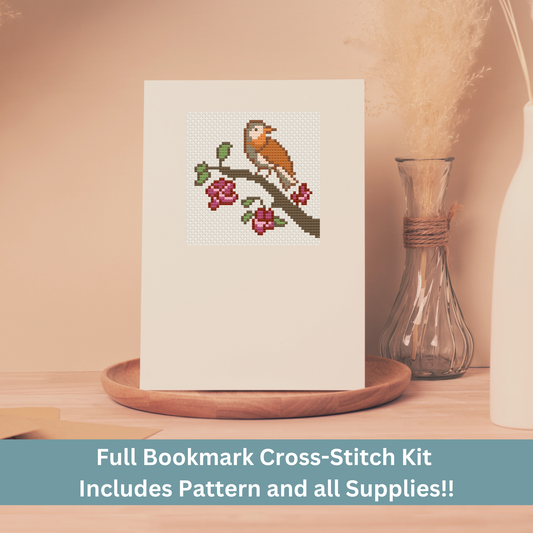 Cross-stitch greeting card featuring a small bird perched on a blossoming branch, stitched on Aida cloth.