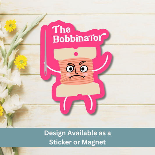 ‘The Bobbinator’ magnet flat lay on light wood background, showcasing fierce thread bobbin illustration