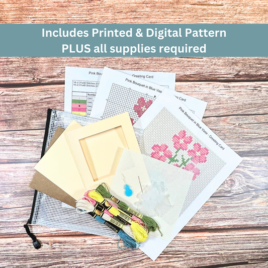 Complete cross-stitch kit featuring a pink bouquet in a blue vase, including Aida cloth, embroidery floss, and pattern sheets.