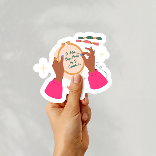 A hand holding a playful embroidery sticker with diverse hands and the quote “I Like Big Hoops & I Cannot Lie”