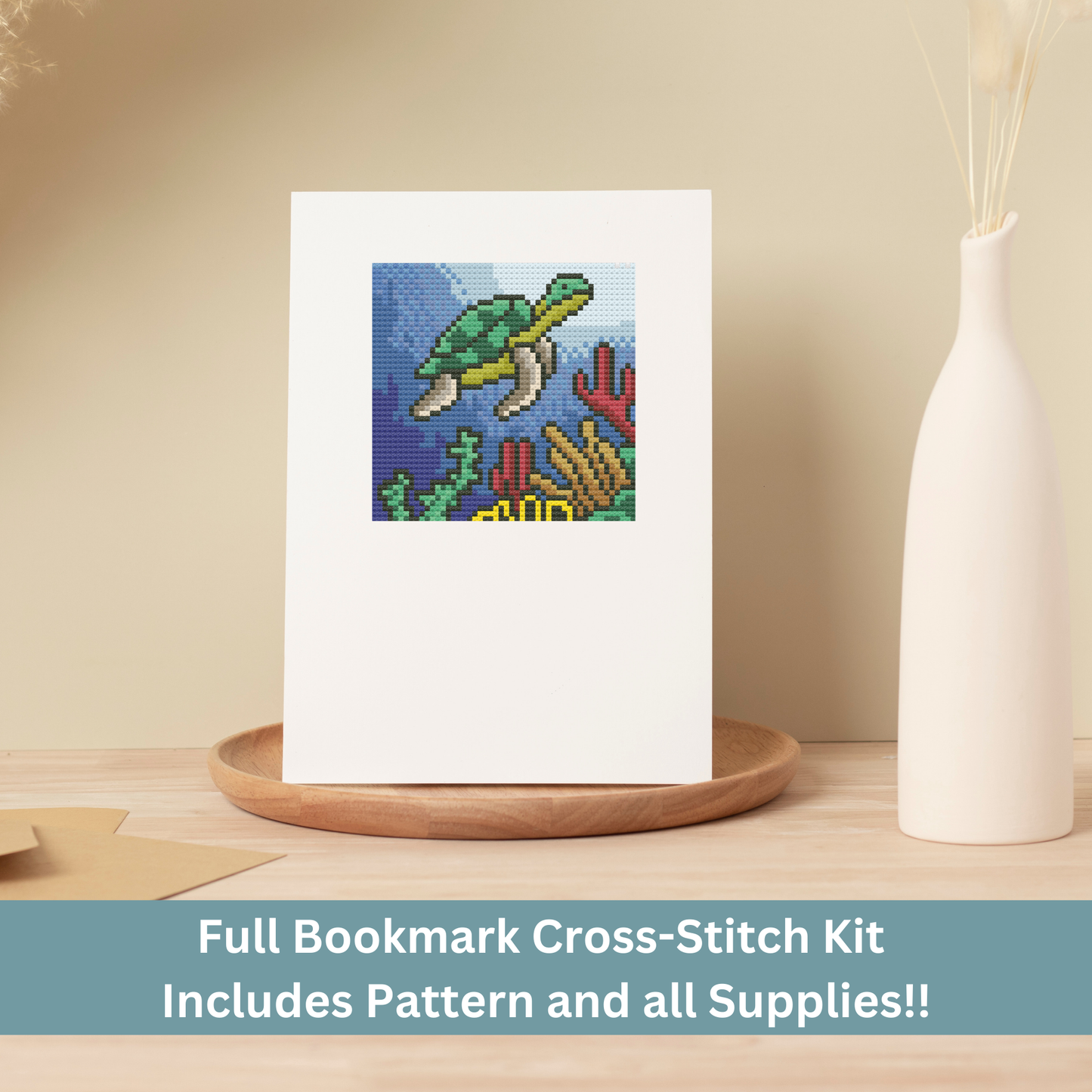 A finished cross-stitch greeting card featuring an underwater sea turtle, displayed on a wooden tray.